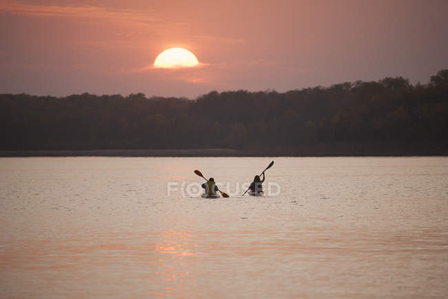 Dois kayakers em barcos ao pôr do sol em lago calmo no Canadá
. — Fotografia de Stock