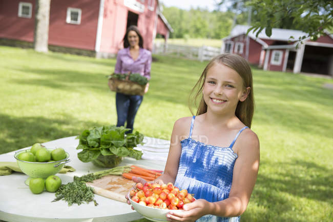Girl carrying bowl of freshly picked cherries at garden table. — Stock Photo