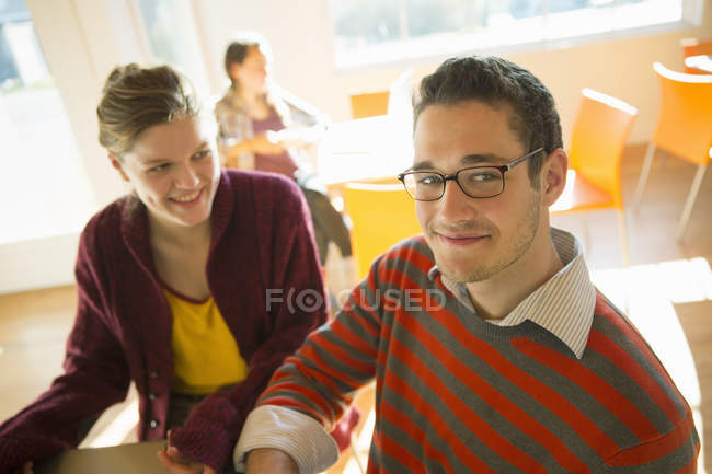 Young man and woman sitting at counter in coffee shop and looking in camera. — Stock Photo