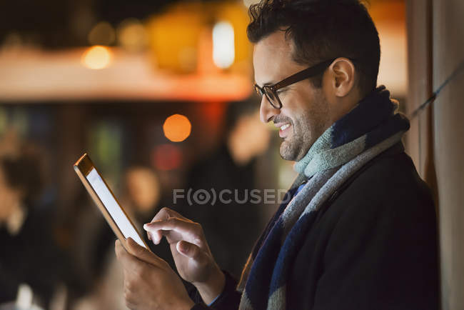 Vista lateral do homem olhando para tablet computador na cidade à noite . — Fotografia de Stock