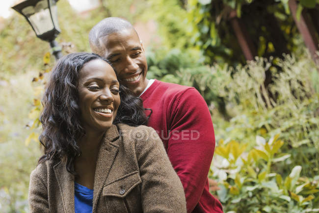 Усміхнений чоловік і жінка обіймає один одного в саду. — стокове фото