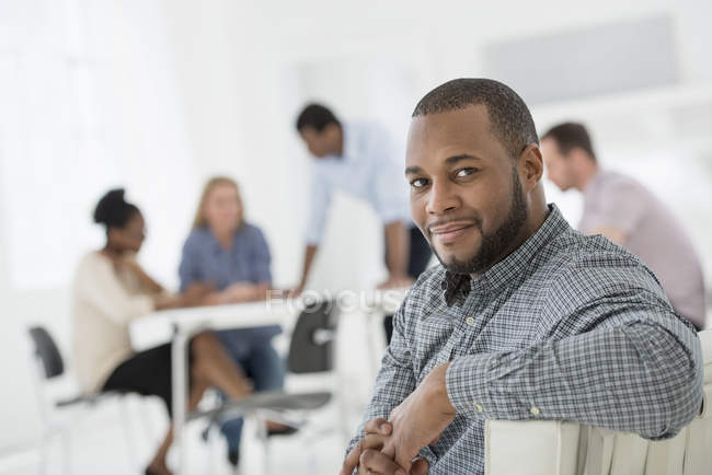 Чоловік середнього віку дивиться через плече в офісному інтер'єрі і колеги на зустрічі . — стокове фото