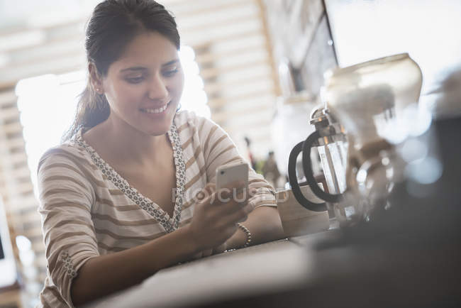 Donna utilizzando smartphone mentre seduto al tavolo della cucina
. — Foto stock