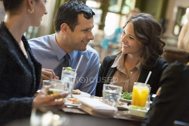 Hombre y mujeres sentados en el bar con bebidas y charlando . - foto de stock
