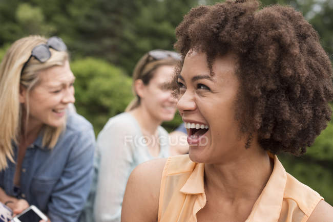 Jovem com afro sorrindo em grupo de amigos ao ar livre . — Fotografia de Stock
