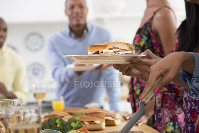 Vista recortada de personas entregando platos de comida a través de la mesa buffet . - foto de stock