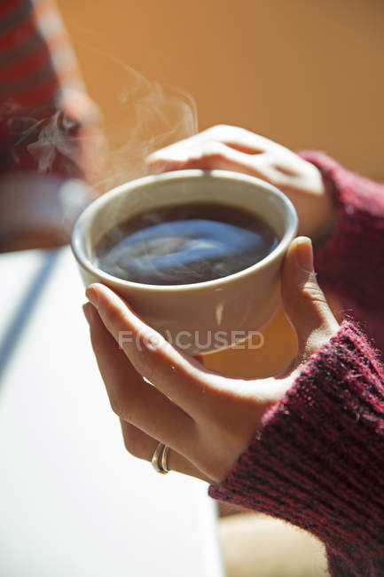 Mains féminines tenant une tasse de café chaud . — Photo de stock