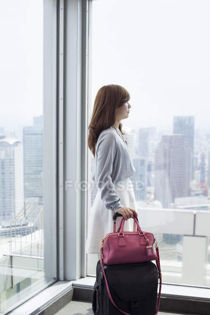 Seitenansicht einer Geschäftsfrau, die Taschen in einem Bürogebäude hält. — Stockfoto