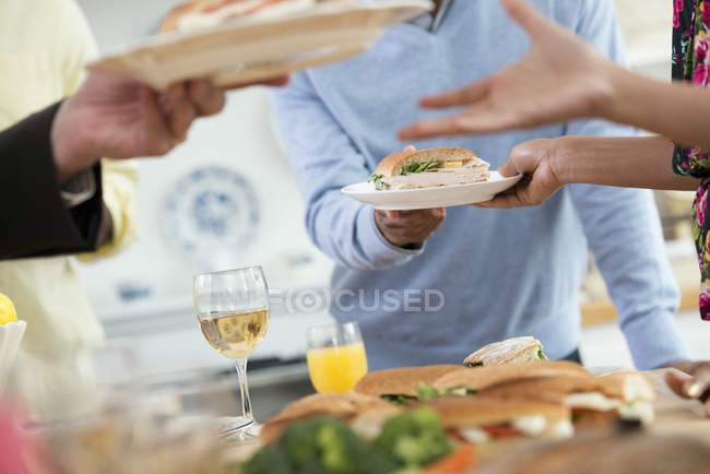 Cropped view of people handing plates of food across buffet table. — Stock Photo