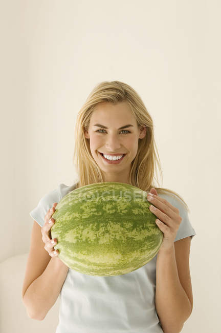 Vue de face de la femme blonde tenant une grande pastèque verte . — Photo de stock