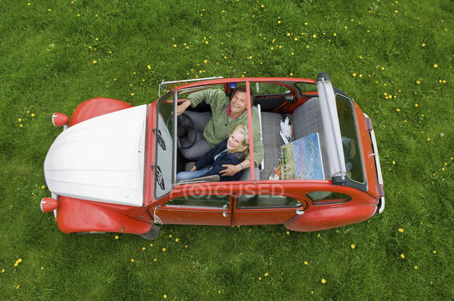 Vista aérea de pareja adulta en coche con techo abierto . - foto de stock