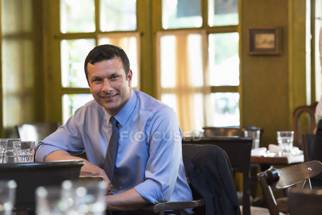 Mann lehnt sich auf Tisch und blickt in Bar-Innenraum in die Kamera. — Stockfoto