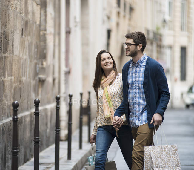 Paar spaziert mit Einkaufstüten durch enge Straße in historischer Stadt. — Stockfoto