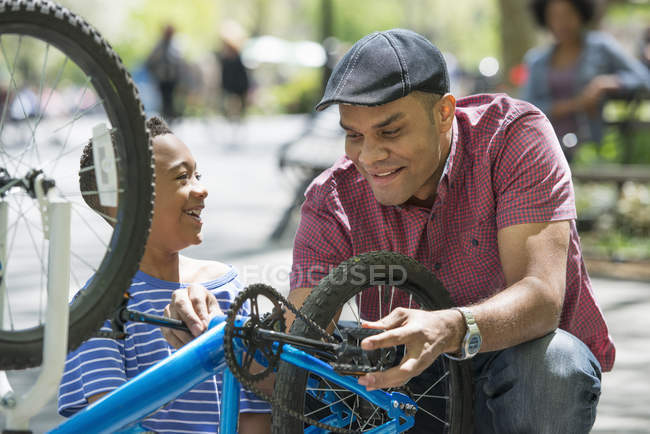 Отец и сын ремонтируют велосипед в солнечном парке . — стоковое фото