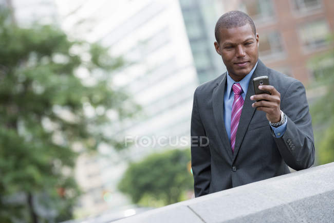 Young businessman in suit using smartphone in city downtown. — Stock Photo