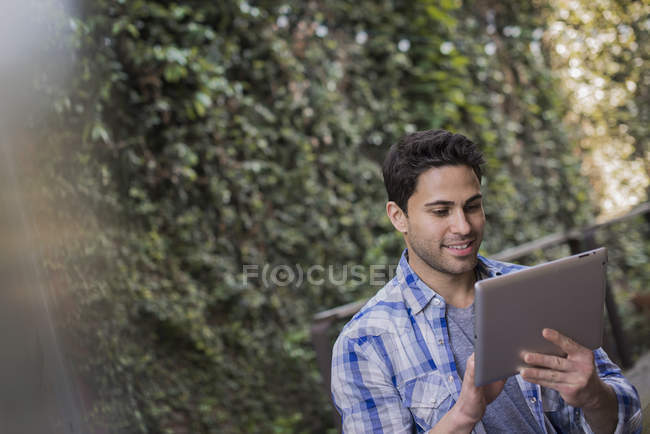 Homem sentado na mesa de café da cidade e usando tablet digital . — Fotografia de Stock