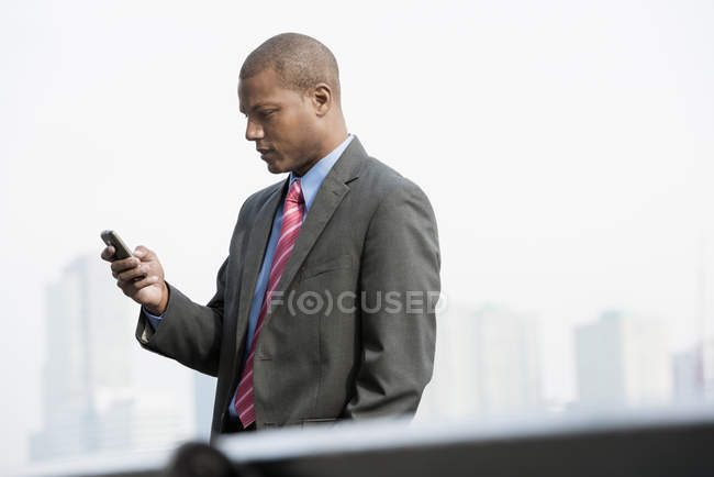 Jovem empresário de terno usando smartphone no centro da cidade . — Fotografia de Stock