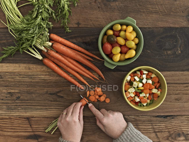 Vue recadrée de la personne coupant des légumes frais sur une table en bois
. — Photo de stock