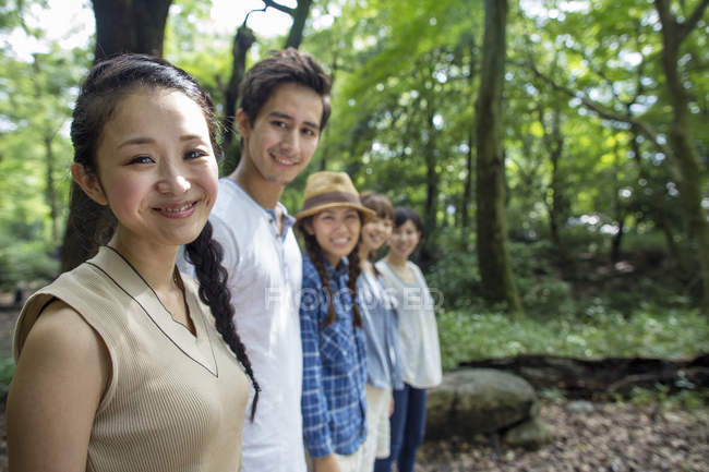 Gruppo di amici asiatici in piedi in fila nella foresta verde . — Foto stock