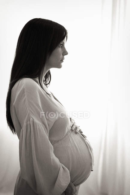 Seitenansicht einer schwangeren Frau mit der Hand auf dem Bauch. — Stockfoto