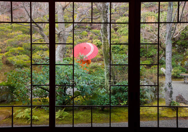 Person standing protected by umbrella in courtyard garden, Kyoto, Japan. — Stock Photo