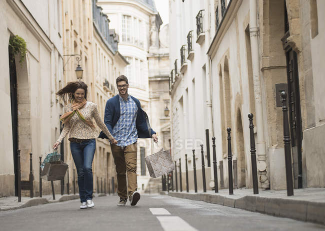 Couple marchant le long d'une rue étroite dans la ville historique avec des sacs à provisions . — Photo de stock
