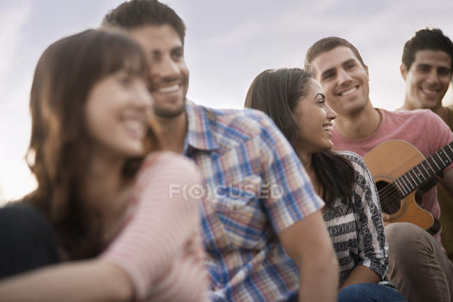 Group of people hanging out at roof party with friends and guitar. — Stock Photo