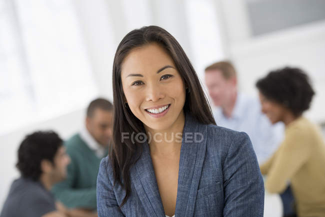 Весела бізнес-леді стоїть в кімнаті для переговорів з колегами на задньому плані . — стокове фото
