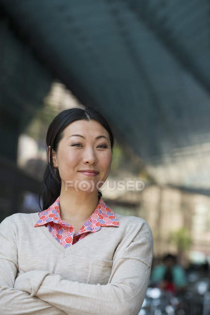 Portrait de femme en chemise rose et pull beige avec bras croisés . — Photo de stock