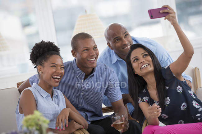 Mujer alegre tomando selfie con amigos con smartphone en la fiesta . - foto de stock