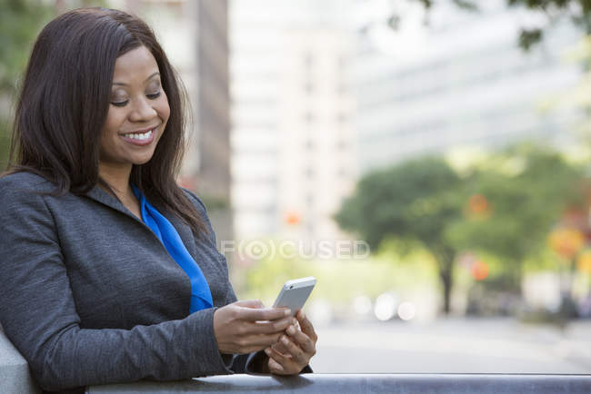 Businesswoman in grey suit using smartphone in city downtown. — Stock Photo