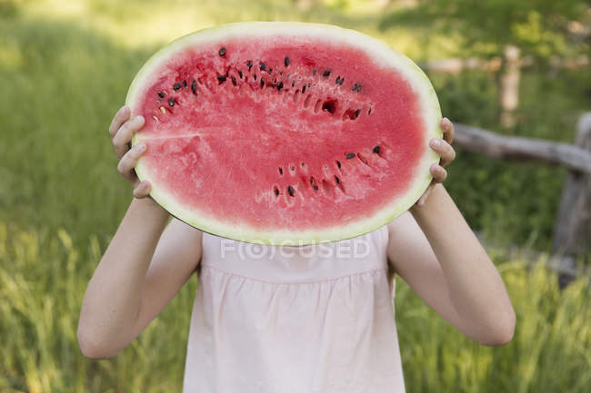 Mädchen hält Hälfte der frischen Wassermelone vor Gesicht. — Stockfoto