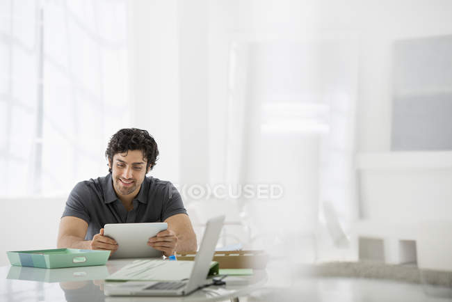 Молодой бизнесмен сидит и использует цифровой планшет за столом в офисе . — стоковое фото