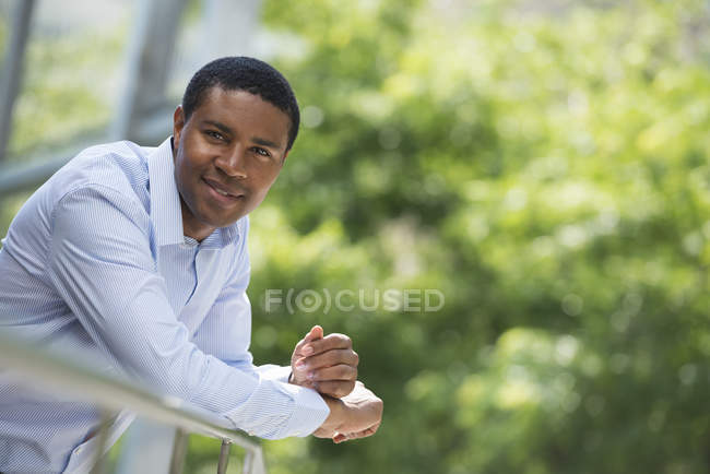 Mid adulto homem inclinado sobre trilhos e olhando na câmera no parque . — Fotografia de Stock