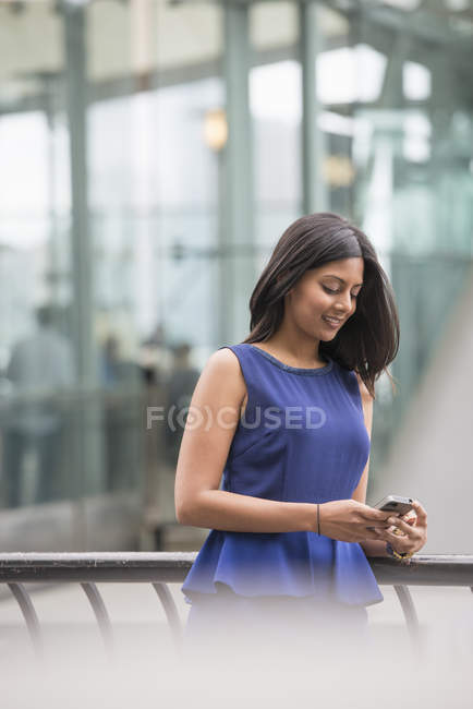 Frau im blauen Kleid checkt Smartphone in der Stadt. — Stockfoto