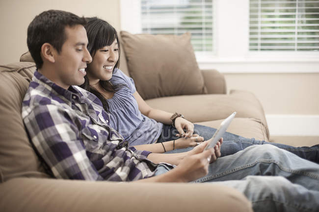 Paar sitzt auf Sofa und nutzt digitales Tablet. — Stockfoto