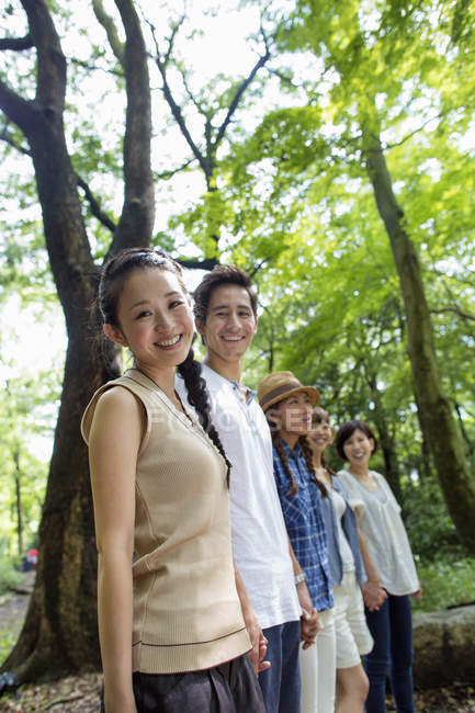 Gruppo di amici asiatici in piedi in fila nella foresta verde . — Foto stock