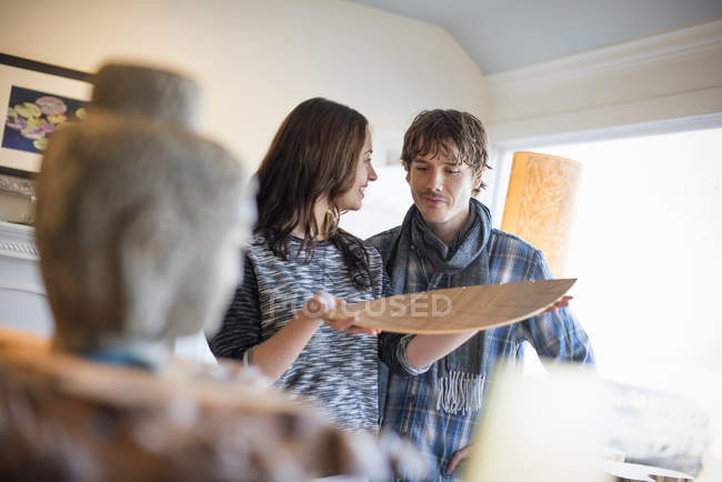 Couple souriant debout dans le salon, femme tenant un plateau en bois . — Photo de stock