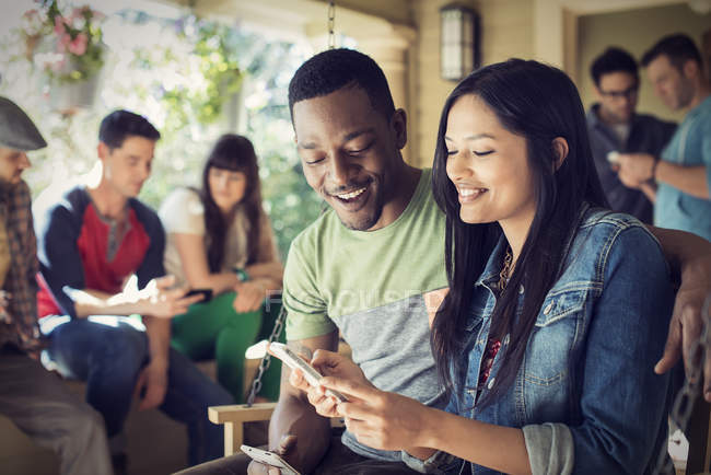 Homme et femme tenant des smartphones avec des démons à la fête de la maison . — Photo de stock