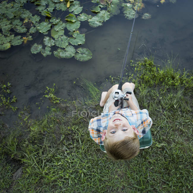 Vue aérienne de l'âge élémentaire garçon pêche en plein air et levant les yeux . — Photo de stock