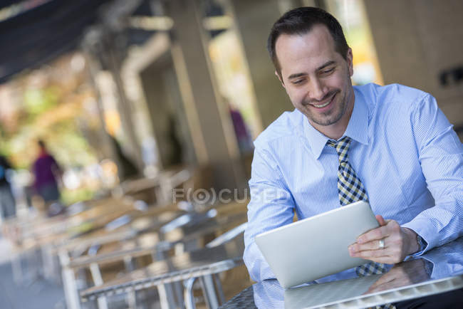 Homem sentado na mesa de café da cidade e usando tablet digital . — Fotografia de Stock
