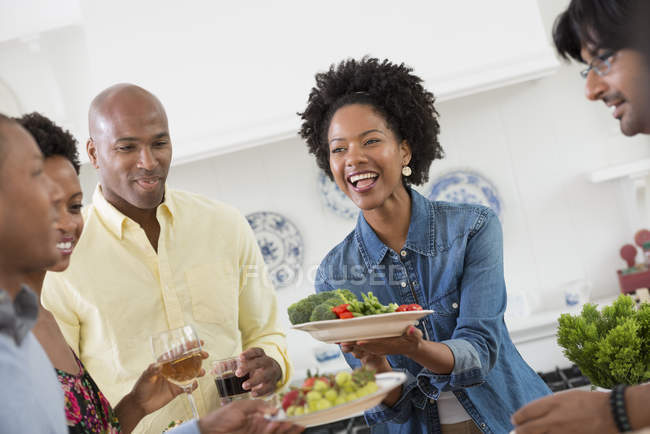 People handing plates of food across buffet table at party. — Stock Photo