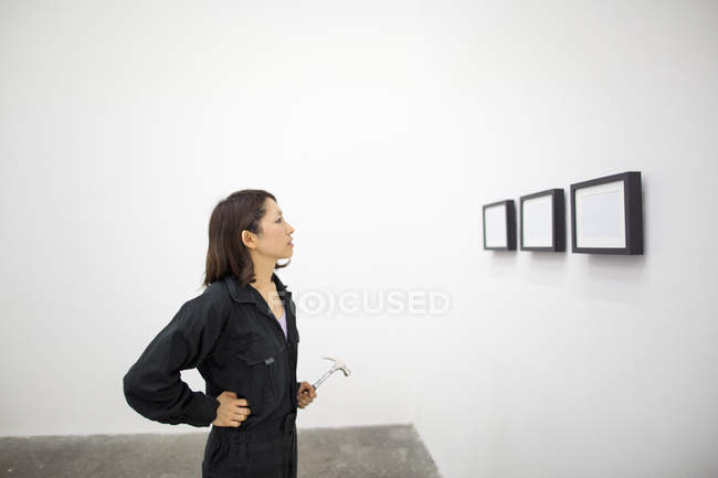 Japanerin mit Hammer und Blick auf zeitgenössische Kunstwerke im Atelier. — Stockfoto