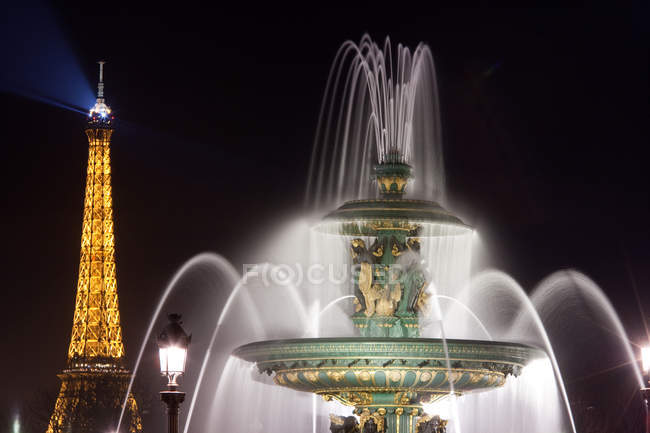 Fuente marítima con la torre Eiffel iluminada detrás en París, Francia - foto de stock
