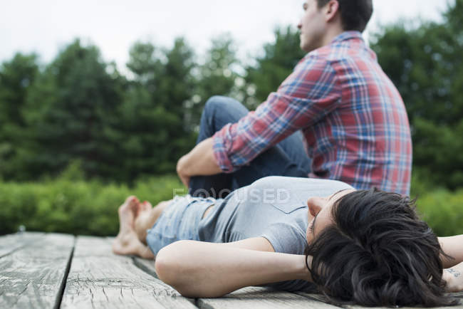 Giovane coppia rilassante sul molo di legno con vista lago di montagna . — Foto stock