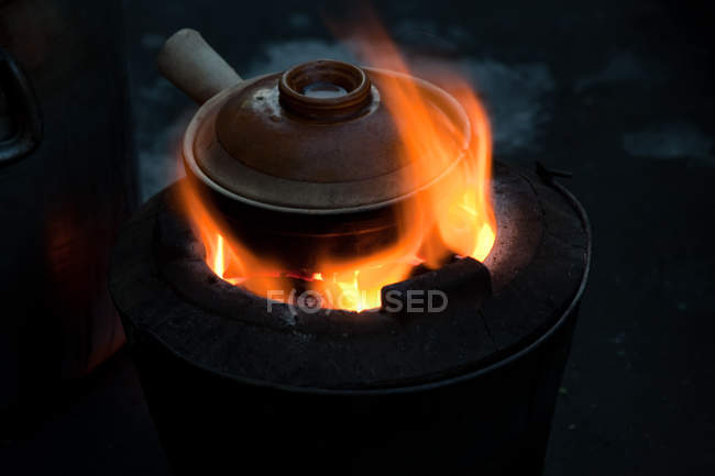 Traditional Asian pot simmering on small barbecue. — Stock Photo