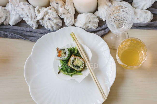 High angle view of plate of sushi and table setting with drinking glasses. — Stock Photo