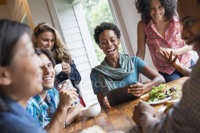 Group of people having lunch and using digital tablet at meeting in cafe. — Stock Photo