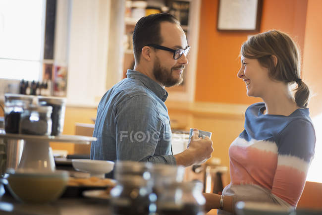 Paar sitzt lächelnd im Café und unterhält sich bei einer Tasse Kaffee. — Stockfoto