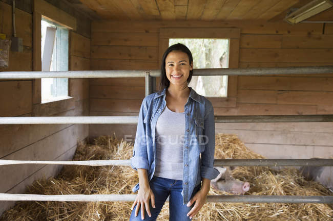 Woman standing beside pig in pen at farm. — Stock Photo